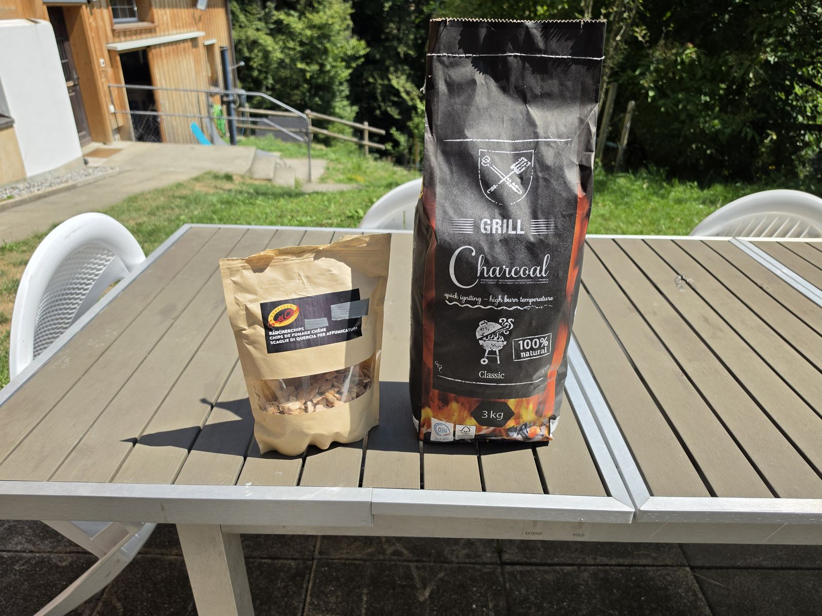 Sack Holzkohle und Räucherchips auf dem Gartentisch