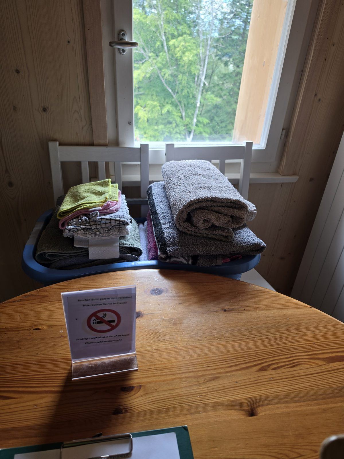 Wäschekorb mit Handtüchern und Putzlappen in der Küche, daneben Hinweisschild zum Rauchverbot